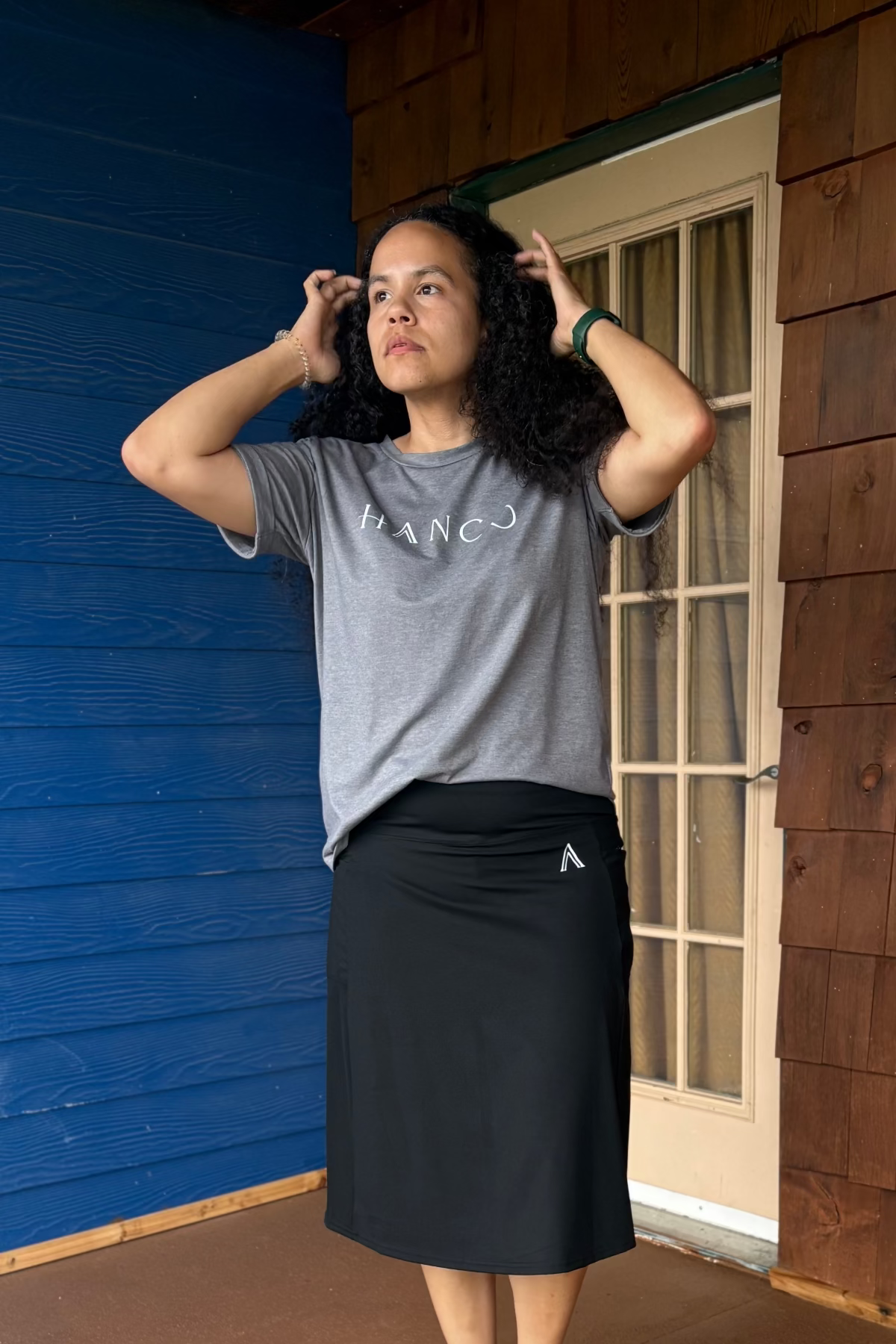 Person wearing headphones standing on a wooden deck with a blue wall and white door in the background.
