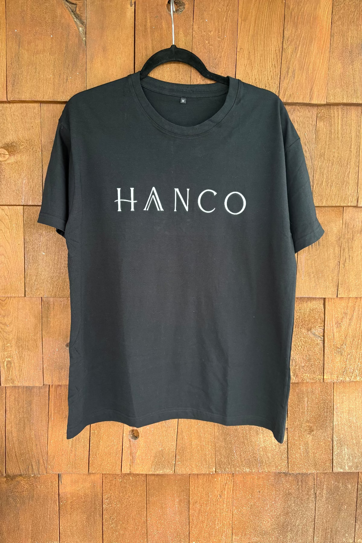 black t-shirt with hanco branding, wooden backgroung