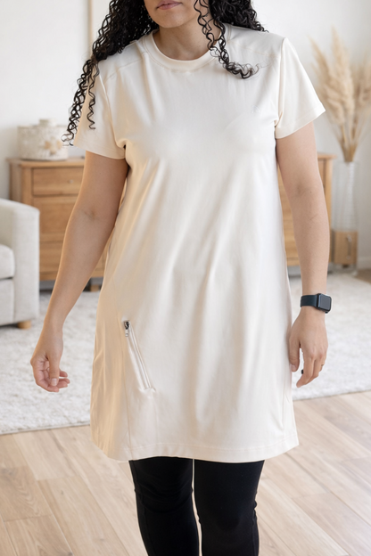 Woman wearing an apricot tunic in a room with neutral decor