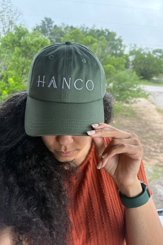 Person wearing a green cap with 'HANCO' text outdoors