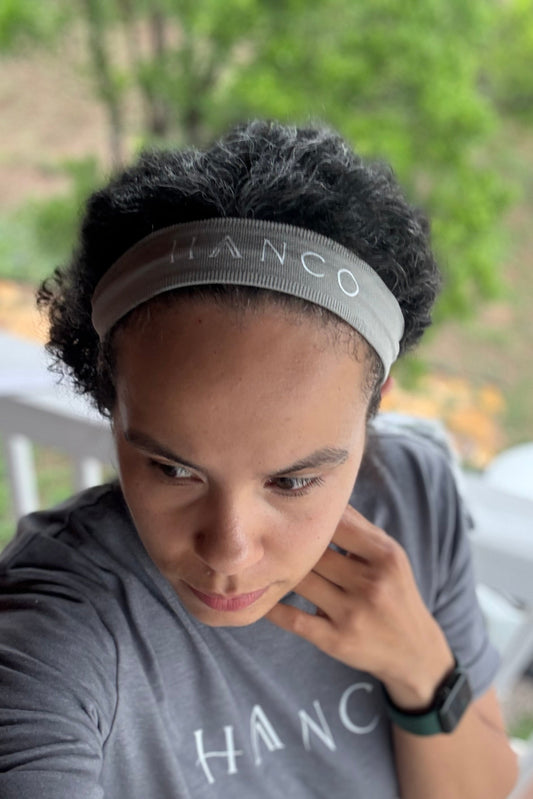 Person wearing a gray 'HANCO' headband and t-shirt on a blurred outdoor background